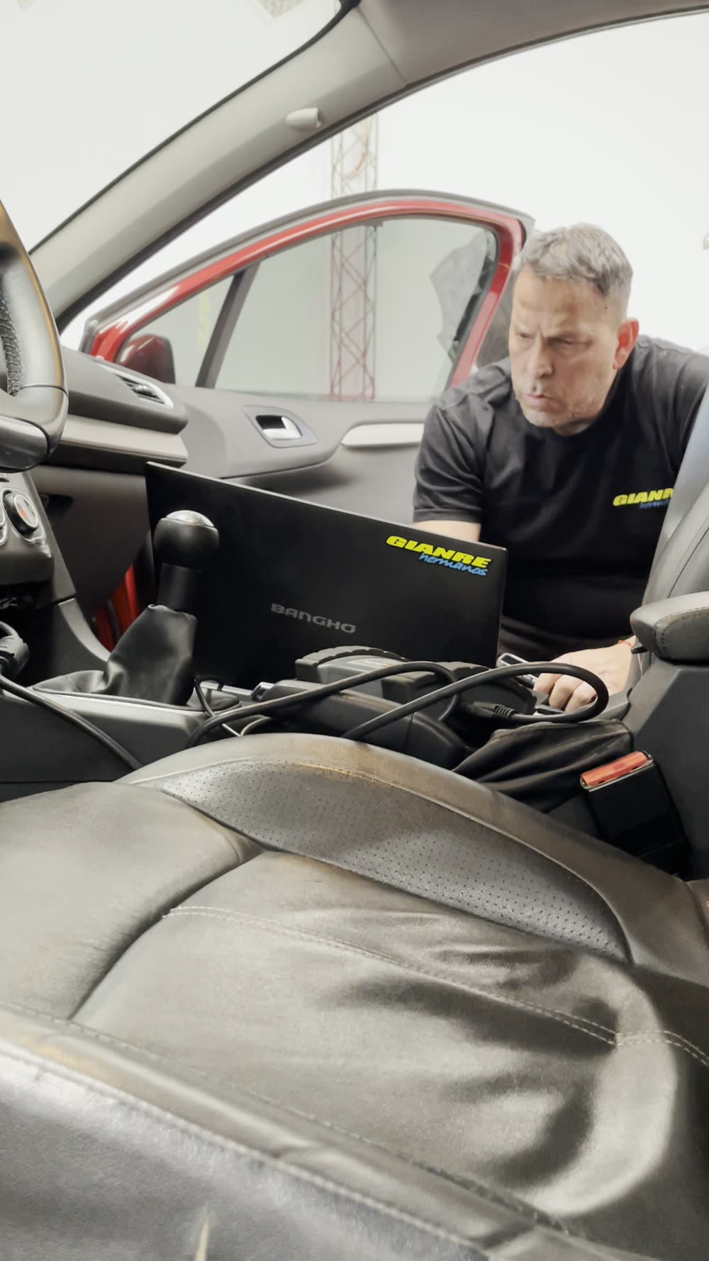 Cuadro del video de Gianre Hnos: un técnico con la notebook de diagnóstico apoyada adentro de un auto